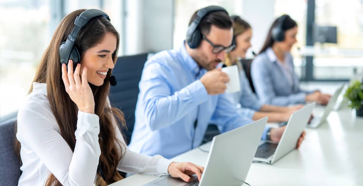 salespeople with headsets in an office using laptops