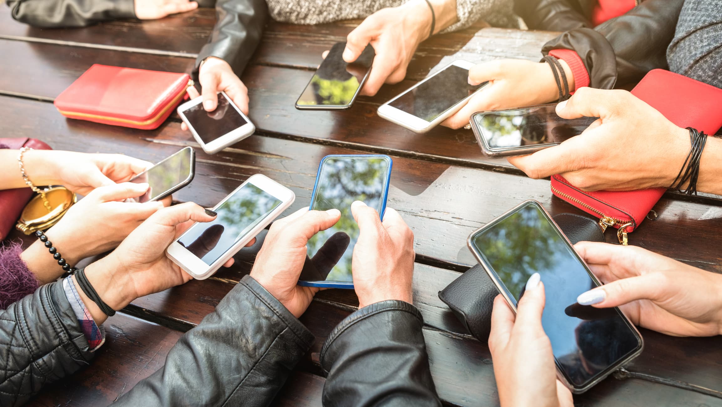 group of friends holding their phones at a table