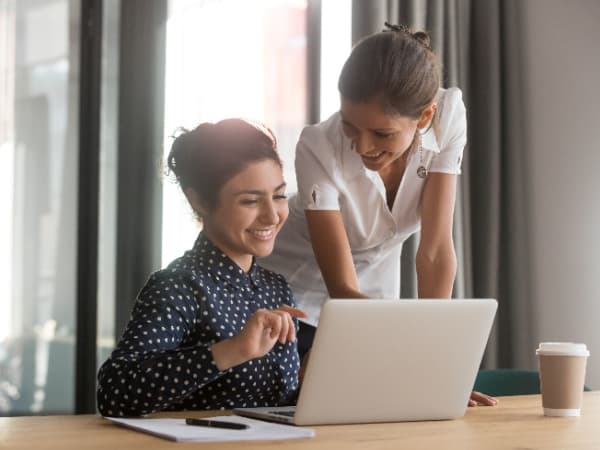 two coworkers talking in front of a laptop
