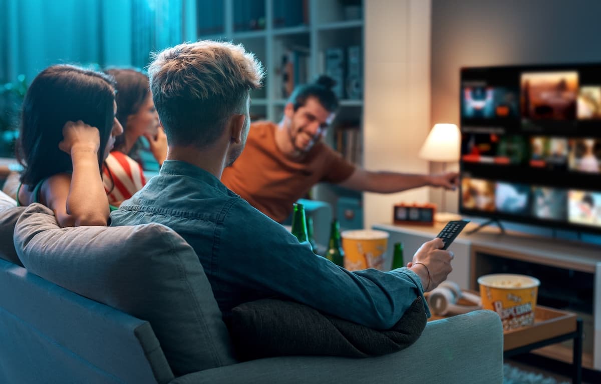 group of young adult friends sitting on a couch watching TV together
