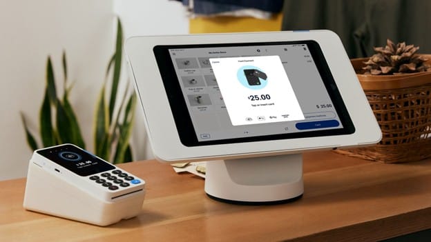 PayPal point-of-sale system showing a touchscreen register and card reader used to process in-person payments.