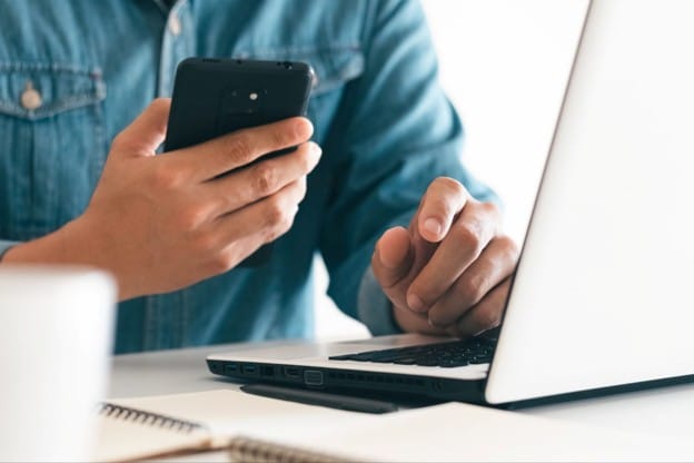 Business user working on a laptop and smartphone with Viasat internet