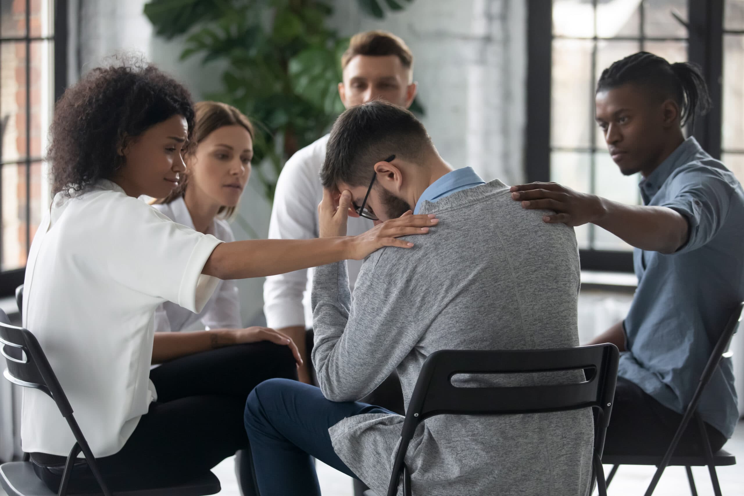 man being comforted by coworkers