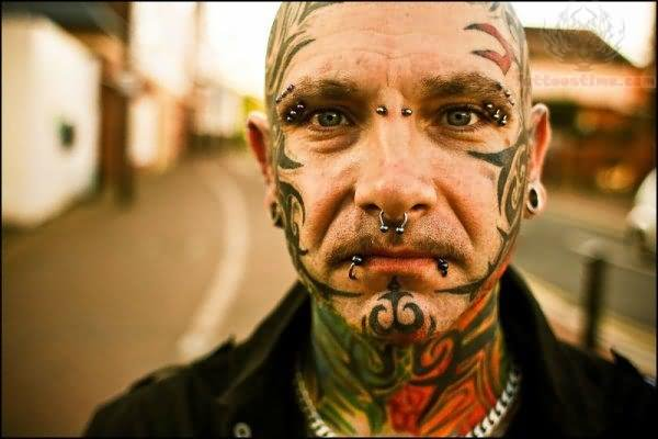 Man with face and neck tattoos and facial piercings
